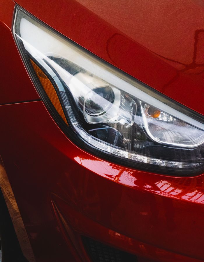 Home Close-up view of a sleek red car headlight reflecting light, highlighting detail and design.
